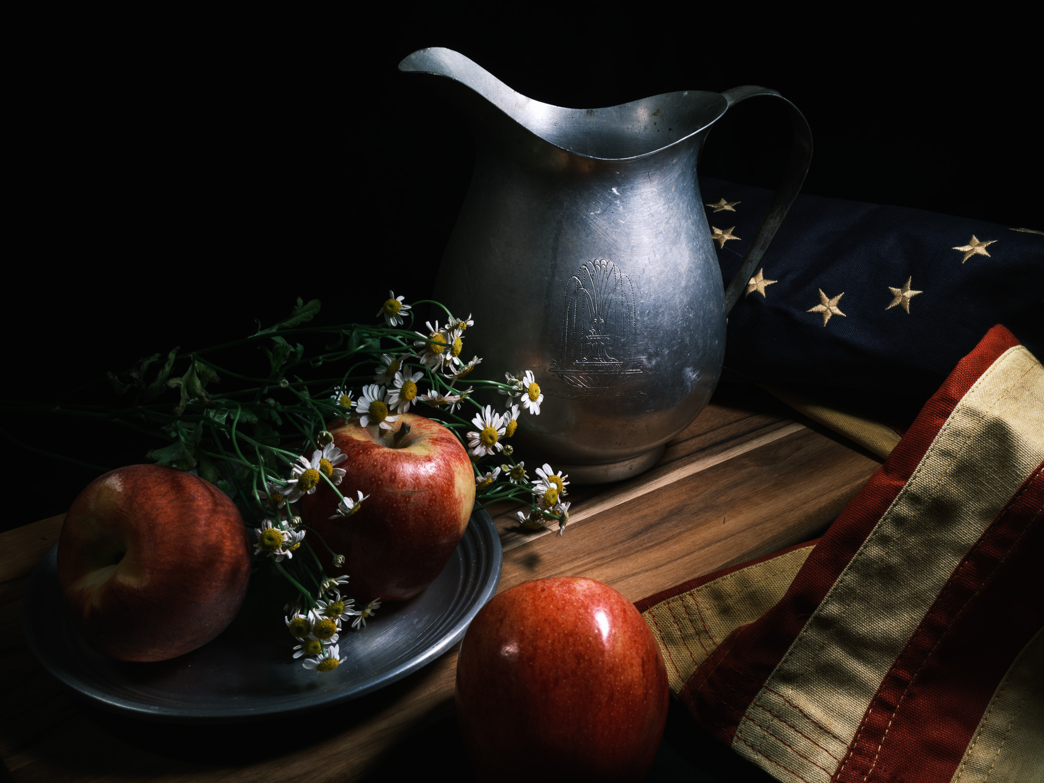 Still-life photography of a colonial flag, flowers, and antqiue water pitcher