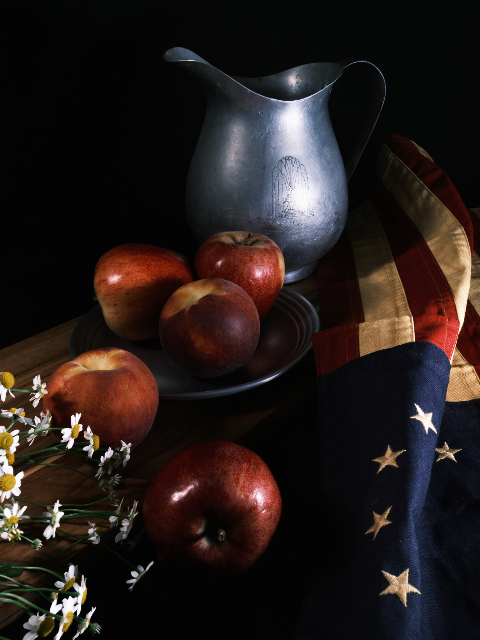 Still-life photography of a colonial flag, flowers, and antqiue water pitcher