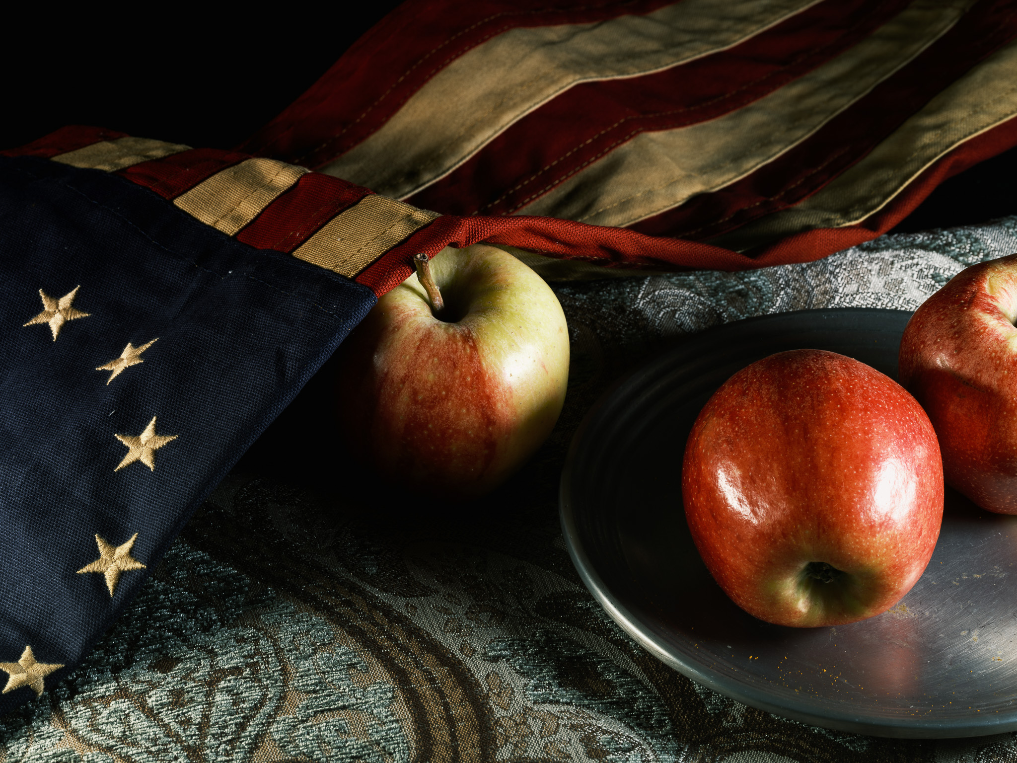 Still-life photography of a colonial flag and apples
                            class=